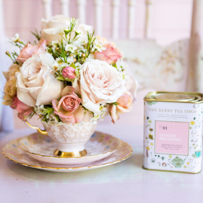 fresh pink roses in antique teacup and box of loose tea leaves