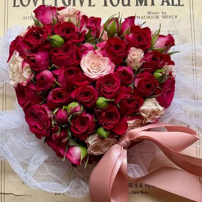 valentines day red roses arranged into a heart shape with pink ribbon